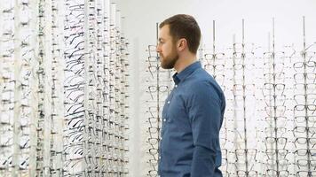 Health care, eyesight and vision concept - a man choosing glasses at optics store video