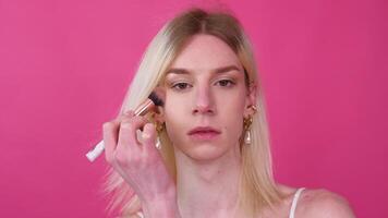 giovane transgender uomo l'applicazione trucco su un' rosa sfondo video