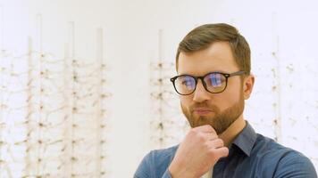 Conceived man choosing glasses at optics store. Health care, eyesight and vision concept video