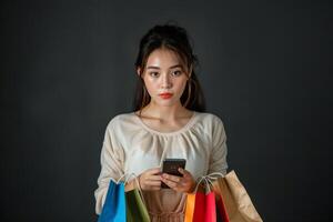 Asian Woman Holding Shopping Bags and Looking at Her Phone photo