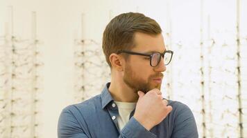 Conceived man choosing glasses at optics store. Health care, eyesight and vision concept video