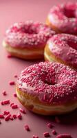 Three Pink Sprinkled Donuts on Pink Surface photo