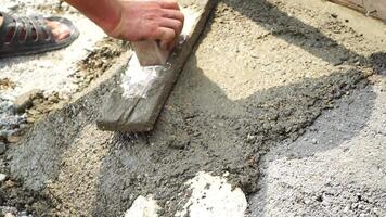 Construction, Worker Hands smooth wet cement in wooden frame at a construction site during daytime to ensure an even surface video