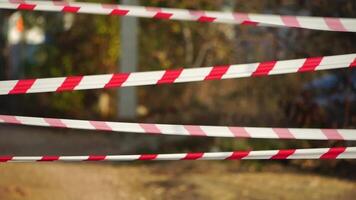 Red and white warning tape swinging in the wind. Protection sign. Don't cross the line. Red White caution tape pole fencing is protects for No entry. Backdrop without people, empty street. video