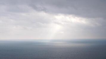 Beautiful rays of sun breaking through the clouds over calm sea ocean. Sunset over the Scenic seascape. Aerial view. Clear overcast background video