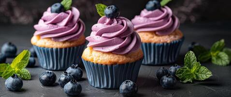 Three Cupcakes With Blueberry Icing and Mint Leaves photo