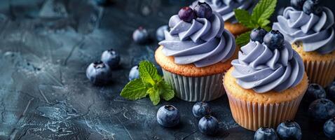 Three Cupcakes With Blueberry Icing and Mint Leaves photo