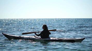 donna mare kayak. contento sorridente donna nel kayak su oceano, paddling con di legno remo. calma mare acqua e orizzonte nel sfondo. attivo stile di vita a mare. estate vacanza. video