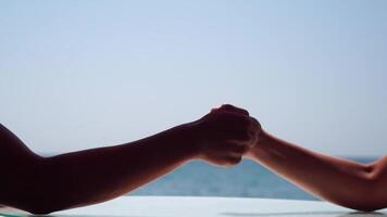 Rock paper scissors being played by two young woman. Close up view female hands playing stone, scissors and paper on sea background, funny carefree game. Friendship, dealing with conflict, having fun. video