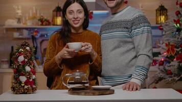 pOV av par leende och ser på kamera i kök dekorerad för jul eve firande. porträtt av festlig människor känsla mysigt i vinter- säsong beredd för Semester fest video