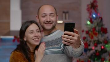 Close up of festive couple talking on call using smartphone for christmas holiday. People chatting on online conference with family for december celebration. Winter season video