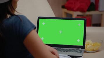 stänga upp av person tittar på horisontell grön skärm på bärbar dator. kvinna ser på krom nyckel på modern enhet med isolerat bakgrund och attrapp mall. vuxen med grej skärm video