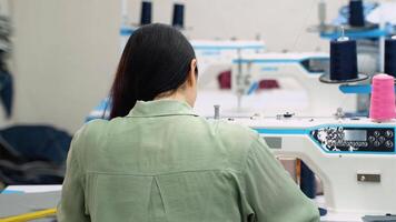 mujer Sastre trabajando a el de coser fábrica. espalda ver video