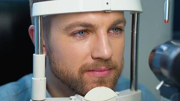 paciente dentro oftalmologia clínica. bonito jovem homem é verificação a olho visão dentro moderno oftalmologia clínica video