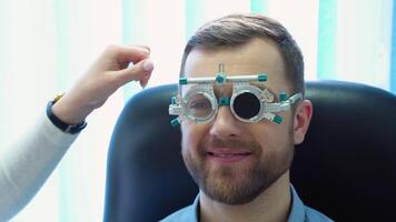 en stilig manlig patient bär särskild oftalmisk glasögon. läkare checkar syn till de patient video