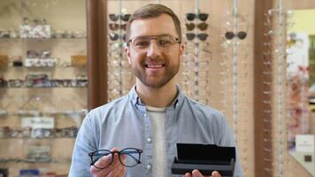 A handsome young man holds a case and glasses in optics video