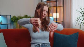 Upset young woman showing thumbs down, dislike bad work, disapproval, dissatisfied feedback at home video