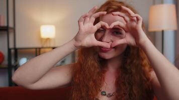 Redhead young woman makes symbol of love, showing heart sign to camera, express romantic feelings video