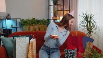Happy redhead woman celebrating birthday party, makes wish blowing burning candle on small cupcake video