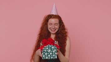 Cheerful young redhead woman opening gift box, unwrapping birthday surprise and expressing happiness video