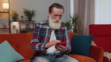 Sénior vieux grand-père homme utilisation téléphone intelligent surpris par mal nouvelles, fortune perte, échouer, loterie résultats video
