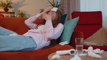 Sick ill child kid suffering from cold or allergy lying on home sofa sneezes wipes snot into napkin video