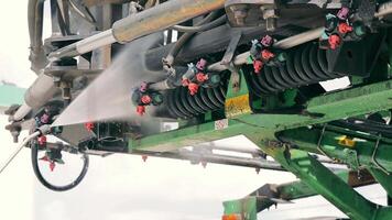 het wassen van agrarisch machinerie met water onder druk. het wassen de sproeier na werken in de veld. onderhoud van apparatuur. video