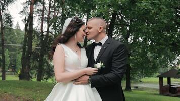 une Jeune couple sur leur mariage journée sont étreindre dans le parc. content jeunes mariés prendre plaisir chaque autres tendresse et touche. video