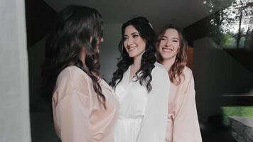 A happy bride and two bridesmaids are posing for the camera, smiling. Wedding morning of the bride and her friends video