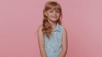 Cheerful lovely young preteen child girl kid smiling, looking at camera on studio pink background video