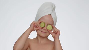 Smiling child girl kid holding slices of cucumber, covering eyes, natural cosmetics, face skin care video