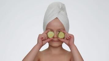 Smiling child girl kid holding slices of cucumber, covering eyes, natural cosmetics, face skin care video