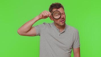 Researcher scientist man holding magnifying glass near face, looking to camera with big zoomed eye video