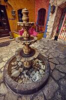 Playa del carmen Mexico 20 august 2022 A colorful courtyard with a marble fountain in the foreground an example of South American architecture photo