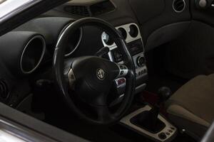 Milan Italy 30 august 2022 Alfa romeo 156 car interior Improved black steering wheel with red stitiching completely black interior photo