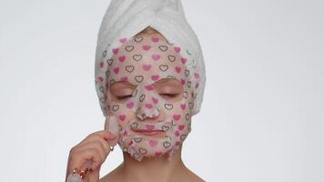 Lovely young smiling child girl applying cosmetic moisturizing face mask, use massage roller video