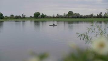 pêcheur nager dans le distance sur une lac, la nature et le silencieux video