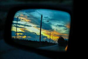 puesta de sol en el vista trasera espejo de el coche foto