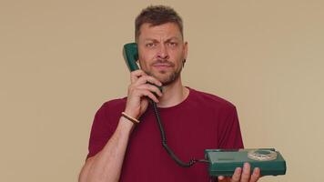 Crazy man in red t-shirt talking on wired vintage telephone of 80s, fooling making silly faces video