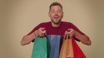 Happy smiling young man showing shopping bags, advertising discounts, amazed with low prices video