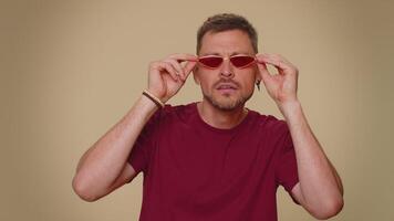 de bonne humeur barbu Beau élégant Jeune homme dans T-shirt et rouge des lunettes de soleil souriant, à la recherche à caméra video