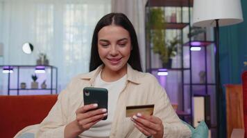 Lovely girl using credit bank card and smartphone, transferring money, purchases online shopping video