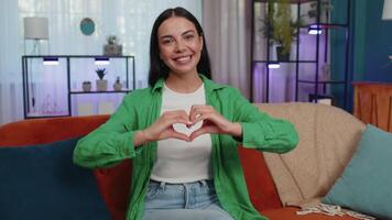 Young woman makes symbol of love, showing heart sign to camera, express romantic positive feelings video