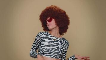 Portrait of seductive pretty young woman with brown lush wig wearing sunglasses, charming smile video