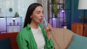 Thirsty one young woman sitting at home holding glass of natural aqua make sips drinking still water video