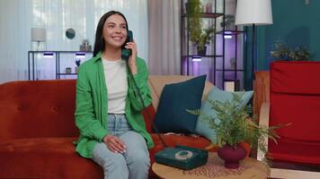 Girl making retro telephone from 90s conversation with friends sitting call on couch at home in room video