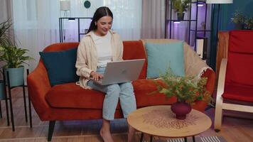 Woman sitting on home couch, looking at camera, making conference call with friends or family video