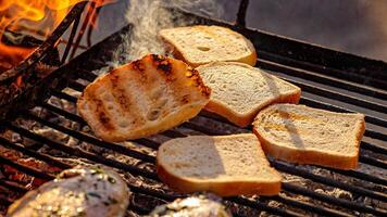 Pieces of white bread are grilling on the open fire outside, photo