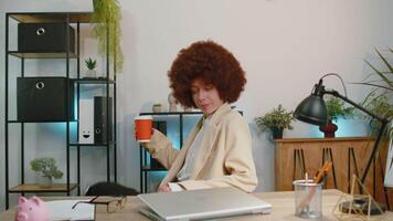 Businesswoman enters office start working on laptop computer at desk and drinking morning coffee video