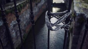 A lanyard tied to a handrail against a canal in the background photo